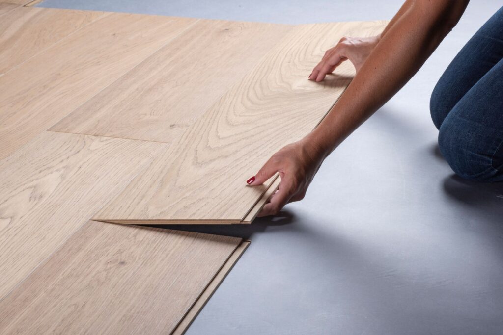Hands lowering a flooring plank in an official Valinge installation photograph